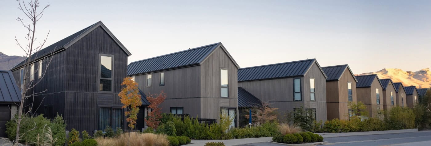 A row of houses featuring black roofs and windows against a clear sky.