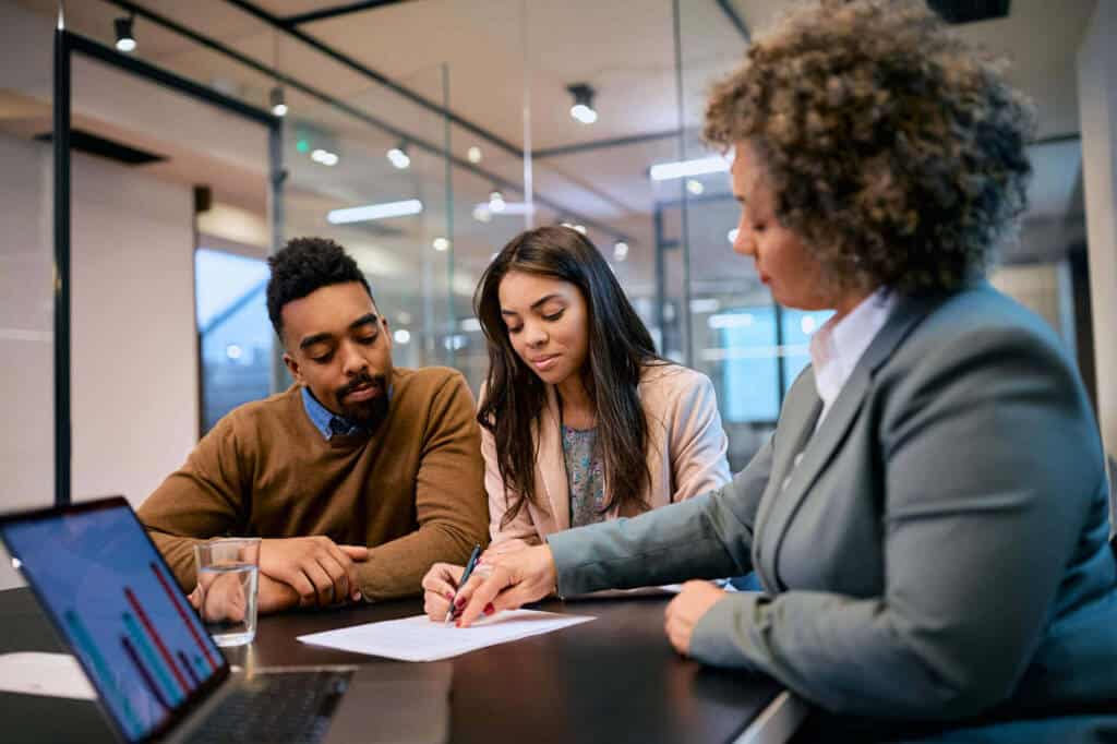 African-American-woman-and-her-husband-signing-mortgage-agreement-during-a-meeting-with-their-bank-manager.